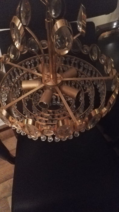 Oupphängd kristallkrona med gyllene finish och klara kristaller, visar två korta och en längre kabel.