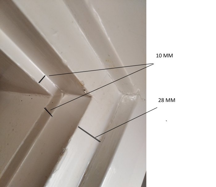 Vitmålad dörrkarm med måttangivelser för tätning, fokus på en skarv med märkta mått 10 och 28 mm.