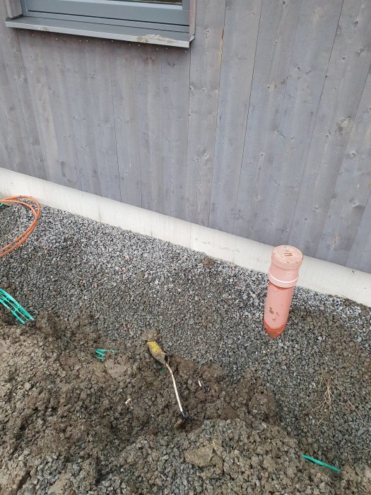 Reparerad elkabel med eltejp bredvid utgrävd fiberledningsgrävning vid husvägg.