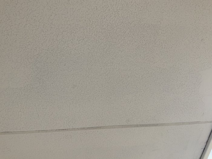 Bild av ett gammalt texturerat tak i ett badrum med synlig skarv och slitage.