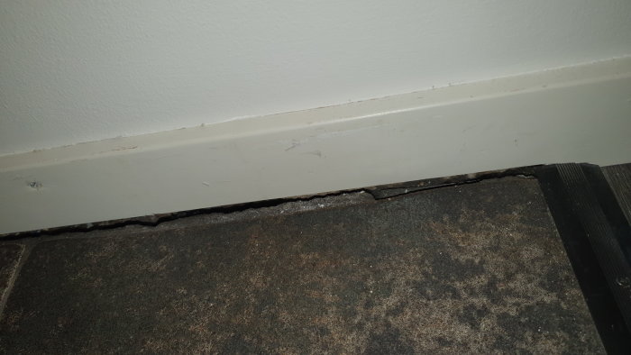 Glipa mellan klinkergolv och vägglist i en hall, med tecken på drag och illa lagt golv.