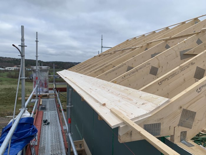 Pågående takarbete på hus med delvis lagd råspont och justerade takstolar.