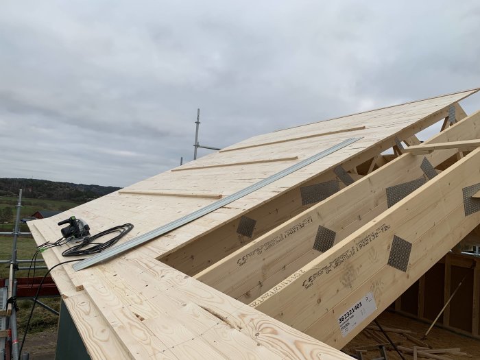 Råspont på takstolar med en cirkelsåg och nytillverkade kilbrädor på en husbyggnadsplats.