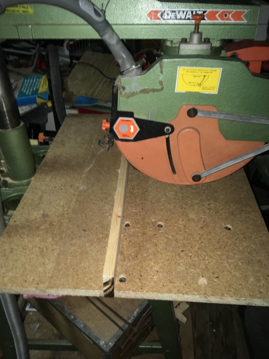 Radialarmsåg med nykluven 45x95-regel på bord, verktyg i bakgrunden.