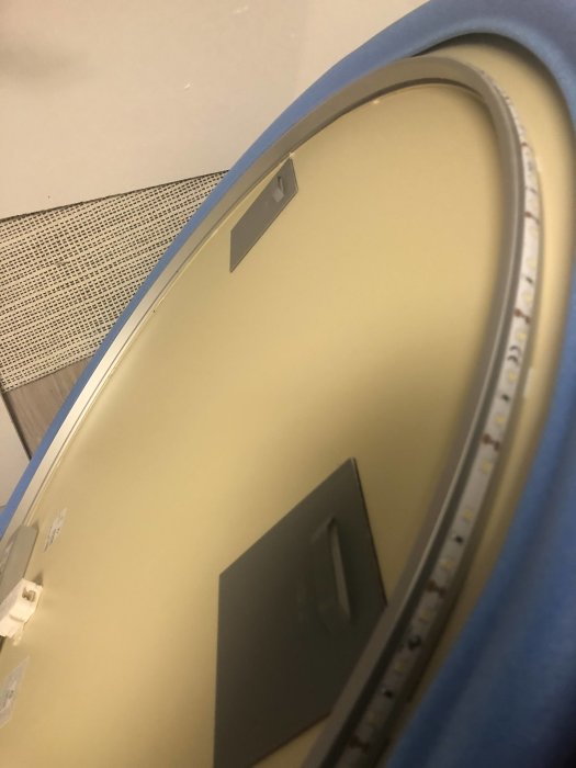 Bakvy på en LED-spegel med synliga väggfästen och en LED-ljusremsa längs kanten, redo för montering.