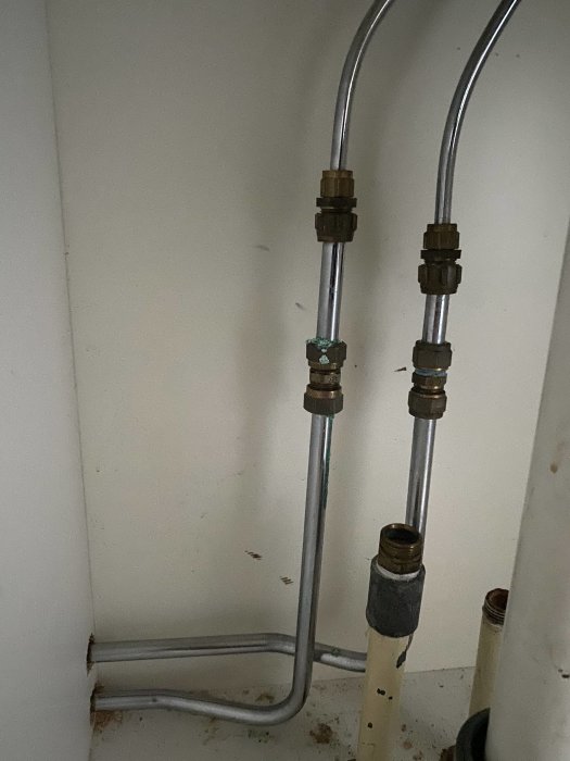 Vattenledningsrör med kopplingar i ett hörn av ett rum, förberedda för installation av vitvaror.