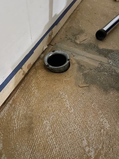 Ventilationsrör som sticker upp ur ett ofärdigt golv vid kökets sockellist.
