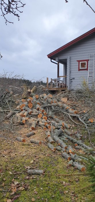 Nykapad ved framför ett rött och grått hus med en veranda, redo för uppvärmning av extra utrymme.