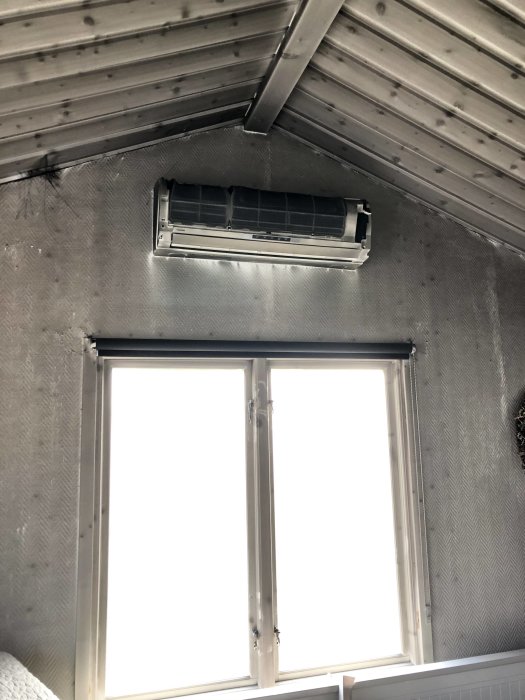 Brandskadat innertak och fönster i ett fritidshus från 60-talet med synliga rökskador och smält plast.