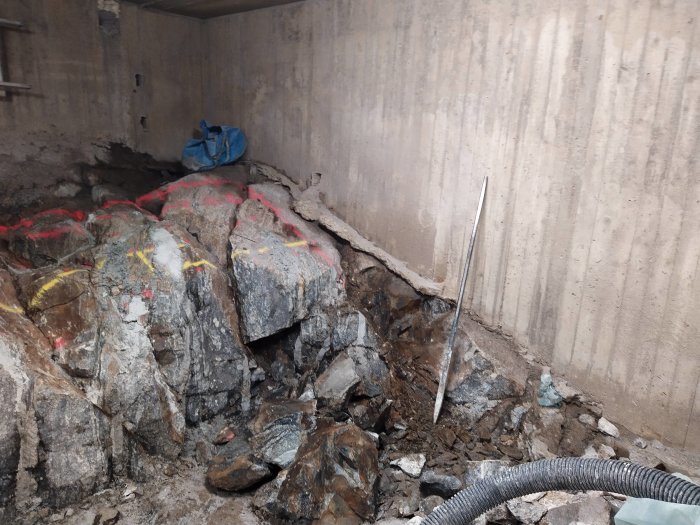Betongrum med splittrad malm och markerade stenblock, eventuell svavelkis, och gruvverktyg.