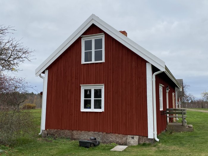 Traditionellt rött svenskt trähus med vita knutar och gavel mot himmel.