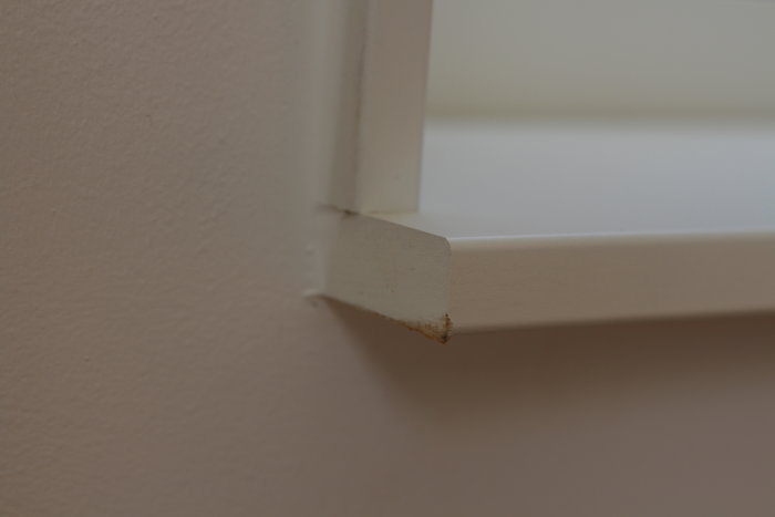 Felaktigt kapad fönstersmyg eller täckbräda med en "kexig" kant som syns mot en vägg.