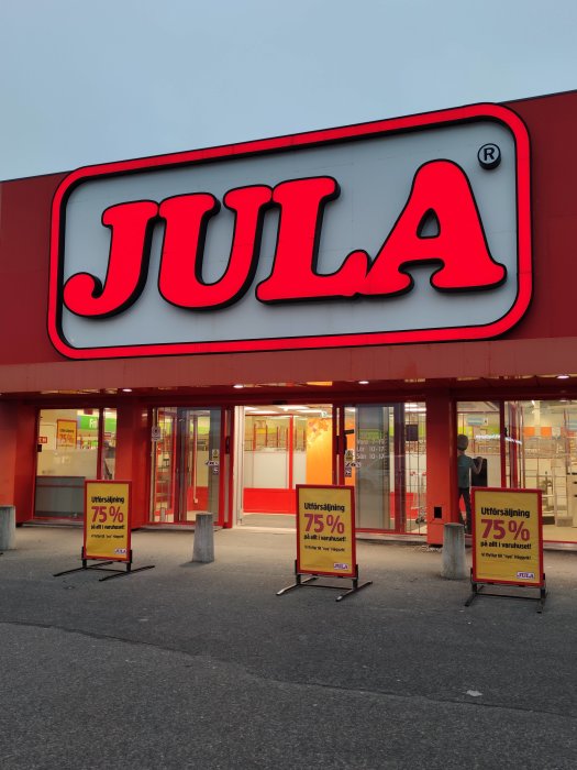 Entrén till Jula-varuhuset med skyltar som annonserar utförsäljning med 75% rabatt.