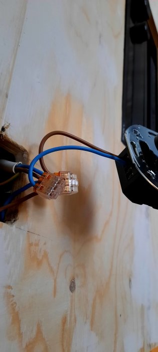 Ouppkopplad dimmer och lösa elkablar framför en trävägg, felaktig anslutning sökes.