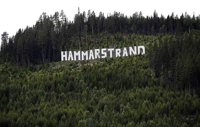 Stora bokstäver som bildar ordet "HAMMARSTRAND" på en skogsbeklädd kulle.