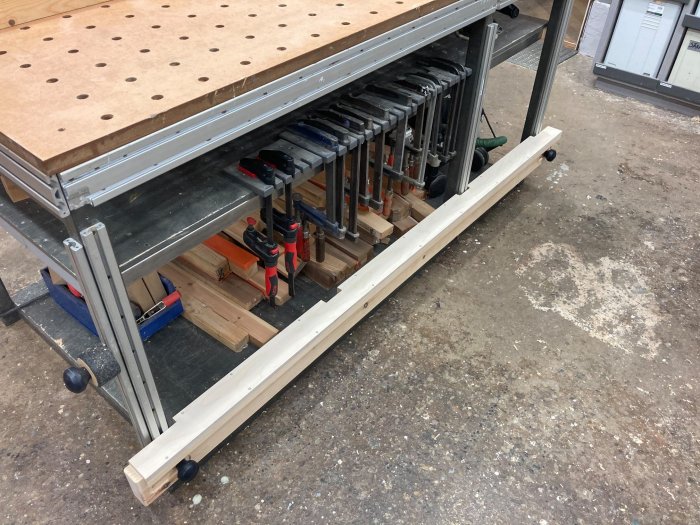 Arbetsbord med uppdaterad sidobalk med outlagd filt, uppställda verktygsklämmor under bordsskivan.