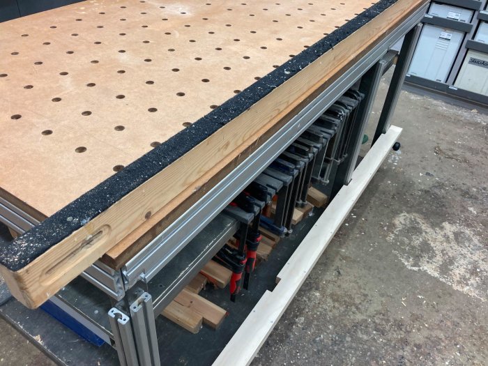 Arbetsbord med perforerad yta och uppdaterad sidobalk med avtagbart lock och ouppklippt filtunderlag.