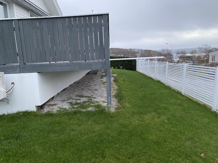 Sida av hus med altan som visar lägsta och högsta punkten, betongblock synliga vid grund.