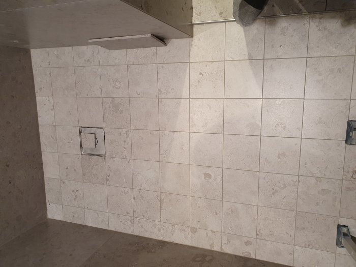Kaklade väggar i sandgrått med 2mm fogar och inbyggda hyllor i en dusch.