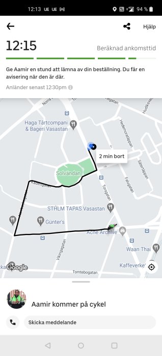 Skärmdump av kartapplikation med leveransspårning, blå ikon visar "2 min bort" och texten "Aamir kommer på cykel".