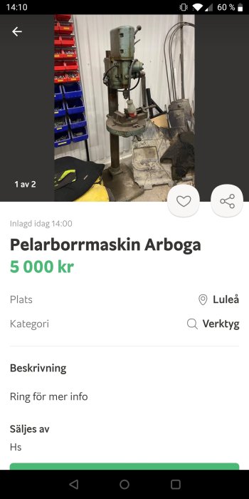 Gammal pelarborrmaskin Arboga i ett verktygsrum med verktygslådor och utrustning i bakgrunden.