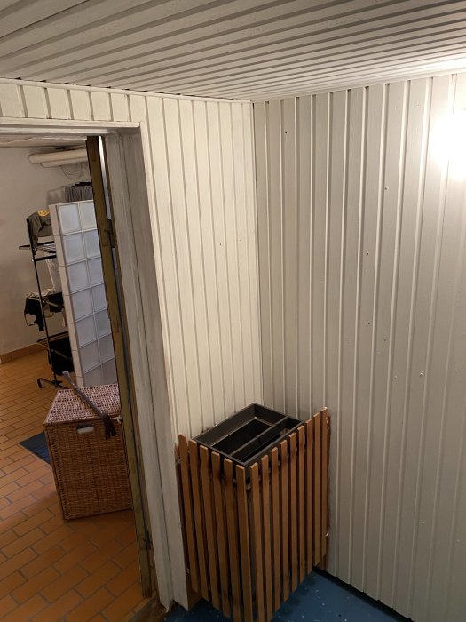Renoverad bastu i källare med ny panel på väggarna, träbänkar och betonggolv.
