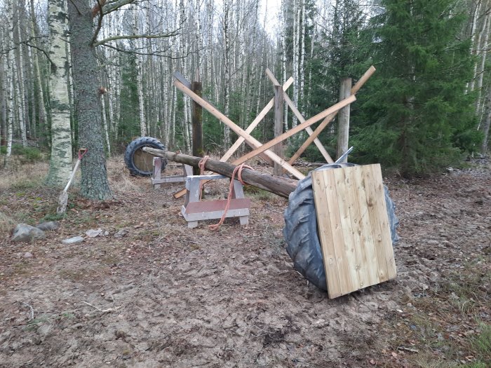 En lång stock uppställd på pallar och däck i skogsmiljö, förberedd för att kortas och lyftas.