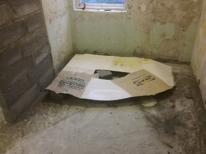 Renoveringsprojekt i badrum med betonggolv och delar av en badkarsmall vid en lättbetongvägg.