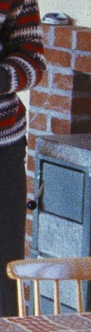 Gammal Handölkamin från 1960 i en sommarstuga, delvis synlig bredvid en person i stickad tröja.