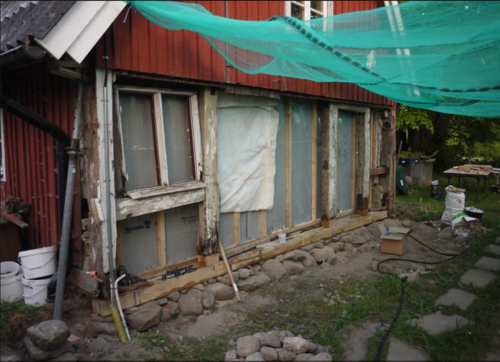 Renovering av skånsk länga, gammalt bortruttnat fotträ byts ut mot nytt vid husgavel.