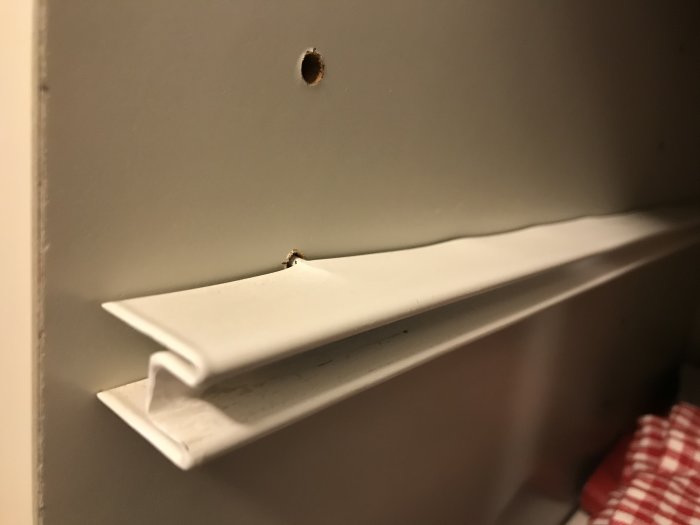 Smalt hyllplan vilar på tunna beslag som riskerar ge vika under tyngd i garderob.
