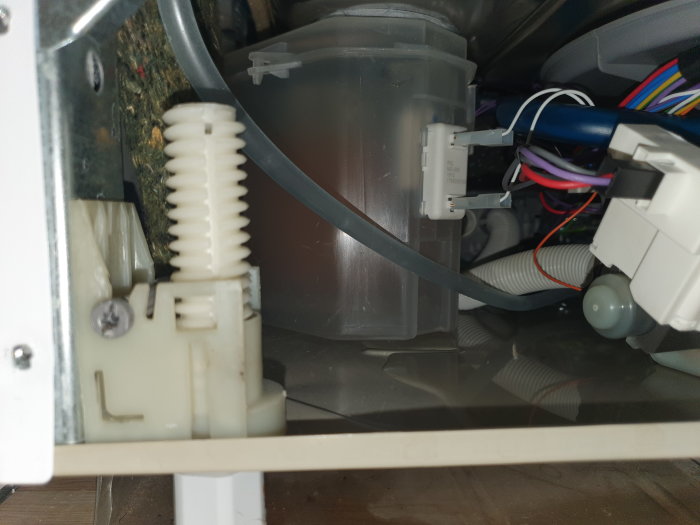 Öppet vitvarus kabinett med synlig löst slangen, kablar och mekaniska komponenter, utan frigolitflotör synlig.