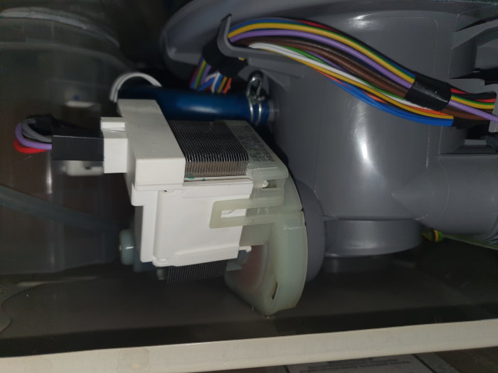 Interiör av diskmaskin med en återansluten slang och synliga elektriska komponenter.