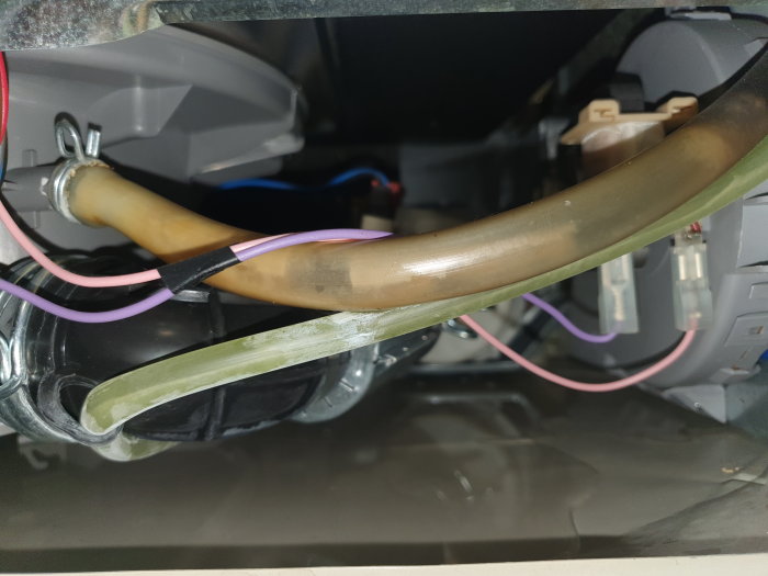 Insida av en apparat med fästa slangar, elektriska kablar och mekaniska komponenter, utan synlig frigolitflotör.