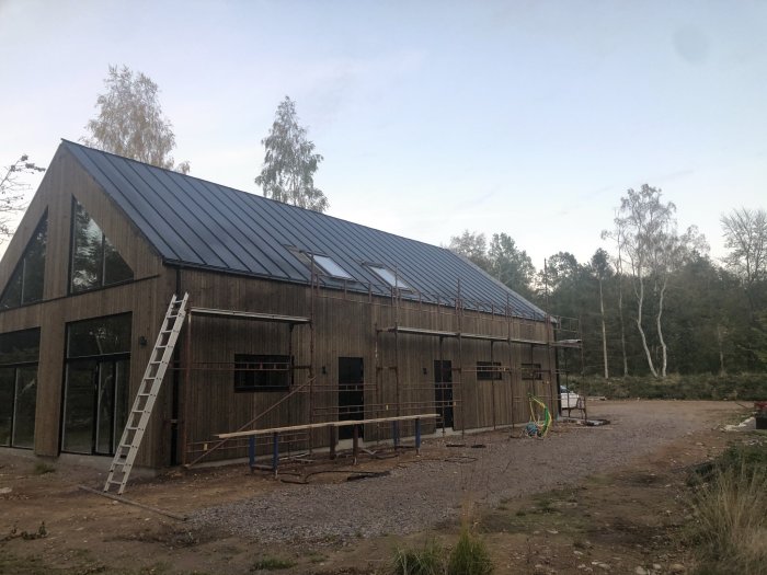 Stort garage under konstruktion med lägenhet ovanpå, stora fönster och tak i plåt.