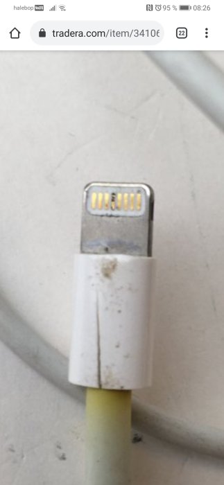 USB-kabelns ändkontakt med smuts och fläckar mot en suddig bakgrund, trots påstått bra skick.