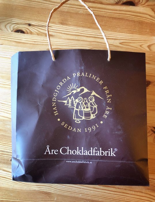 Påse från Åre Chokladfabrik med text och logo på träunderlag.