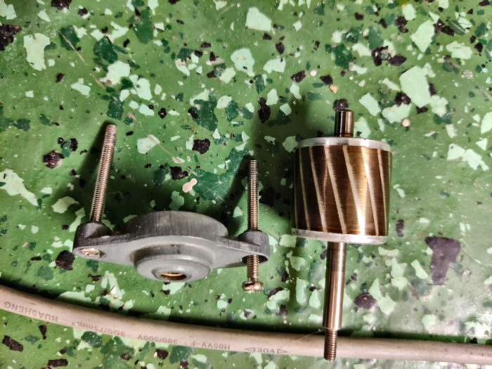 Demonterad motor från en avfuktare med rotor och stator synlig på en fläckig verkstadsbänk.