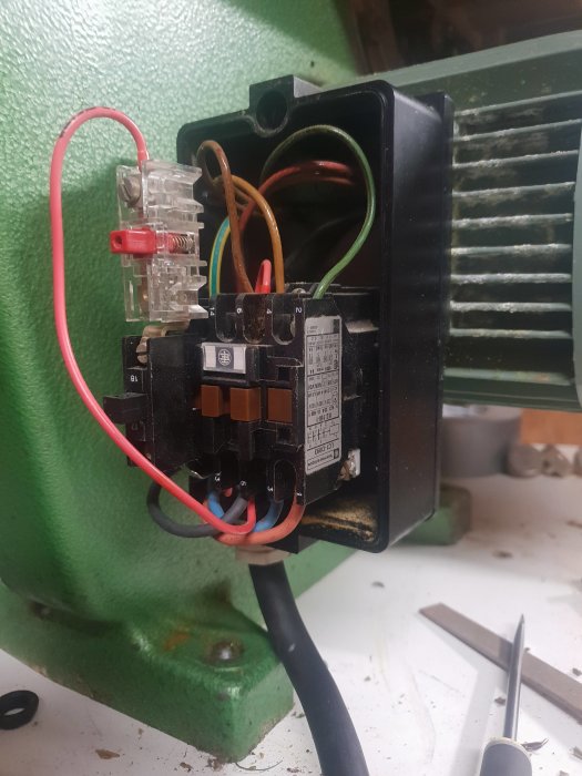 Elektriskt motorskydd och wiring till 3fas motor, verktyg syns på arbetsytan.