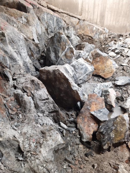 Stora stenblock och spräckt berg i en grusig byggarbetsplats som förberedelse för efterspräckning.