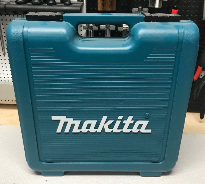 Blå Makita-verktygslåda stänger på ett verktygsbord.