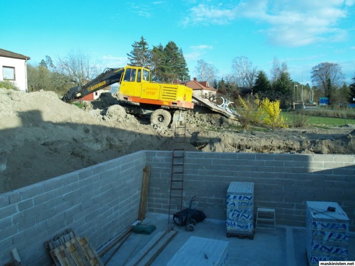 Grävmaskin vid pågående grävarbeten bredvid nylagda betongblock för byggprojekt.