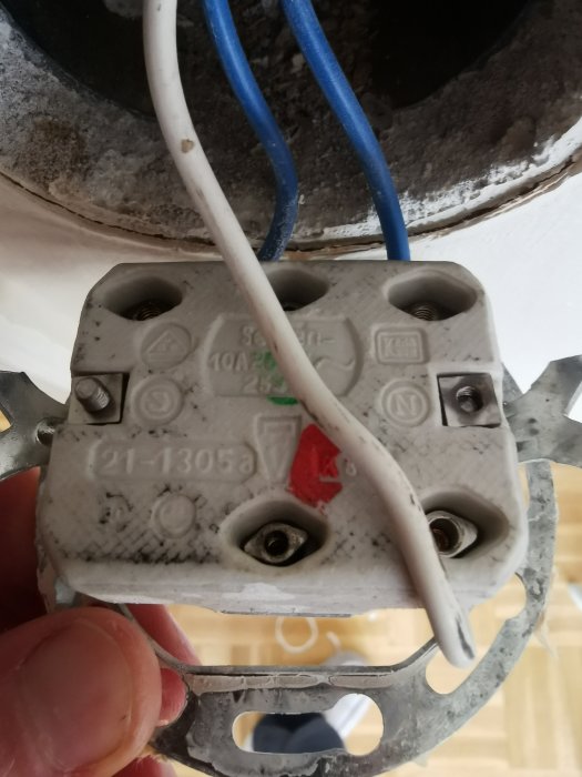 Gamal strömbrytare med vita, blå och gröna kablar anslutna, som ska bytas ut mot en ny Schneider renova.