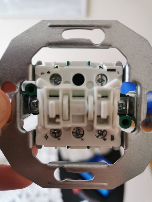 En hand håller en 2-krets kronströmställare Schneider Renova under en installeringsprocess.