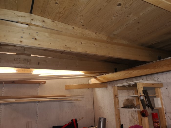 Nybyggt förråds innertak med synliga takbjälkar och bastupanel av trä.