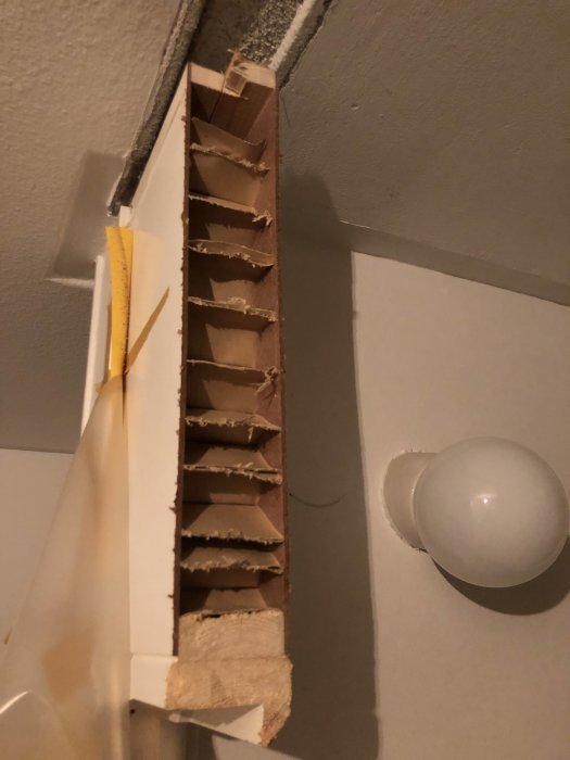 Delvis nedmonterad vägg ovanför dörr visar masonit och 70mm lättbetong i ett badrumsrenoveringsprojekt.