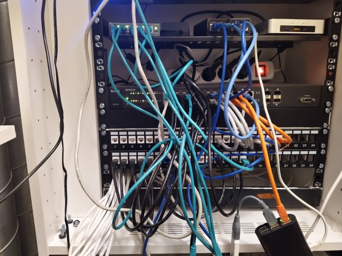 Ett nätverksskåp med organiserade och oorganiserade Ethernet-kablar och nätverksutrustning.