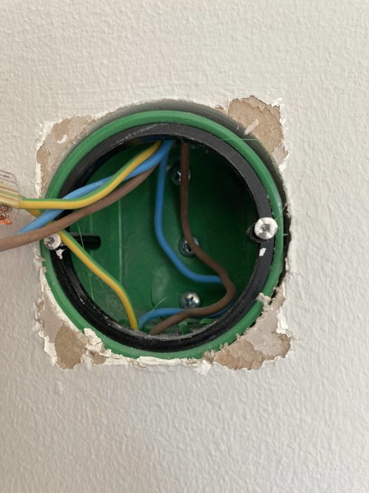 Öppen eldosa i vägg med synliga elektriska kablar och kontakter under installation.