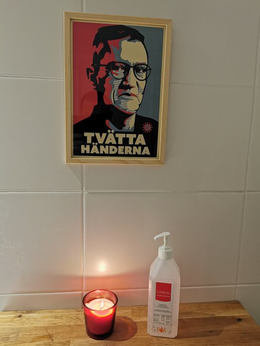 Ett "altare" med en inramad affisch som säger "Tvätta händerna", ett tänd ljus och en handspritflaska.
