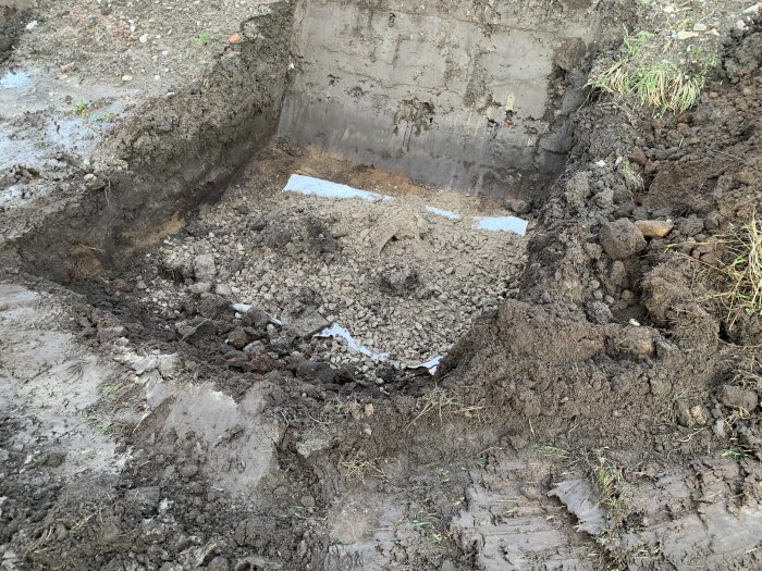 Uppgrävd jord och grundstenar för gjutning av fundament till en carport.